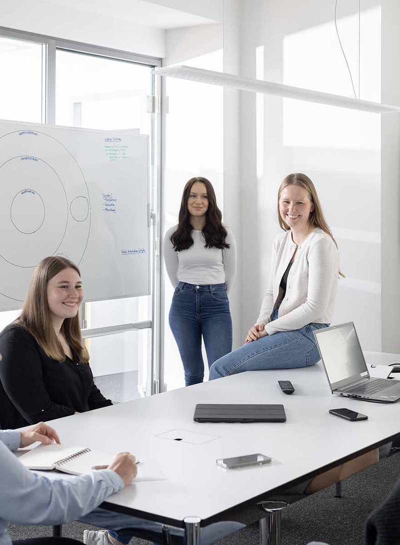 Auszubildende in Teambesprechung mit Whiteboard im Büro