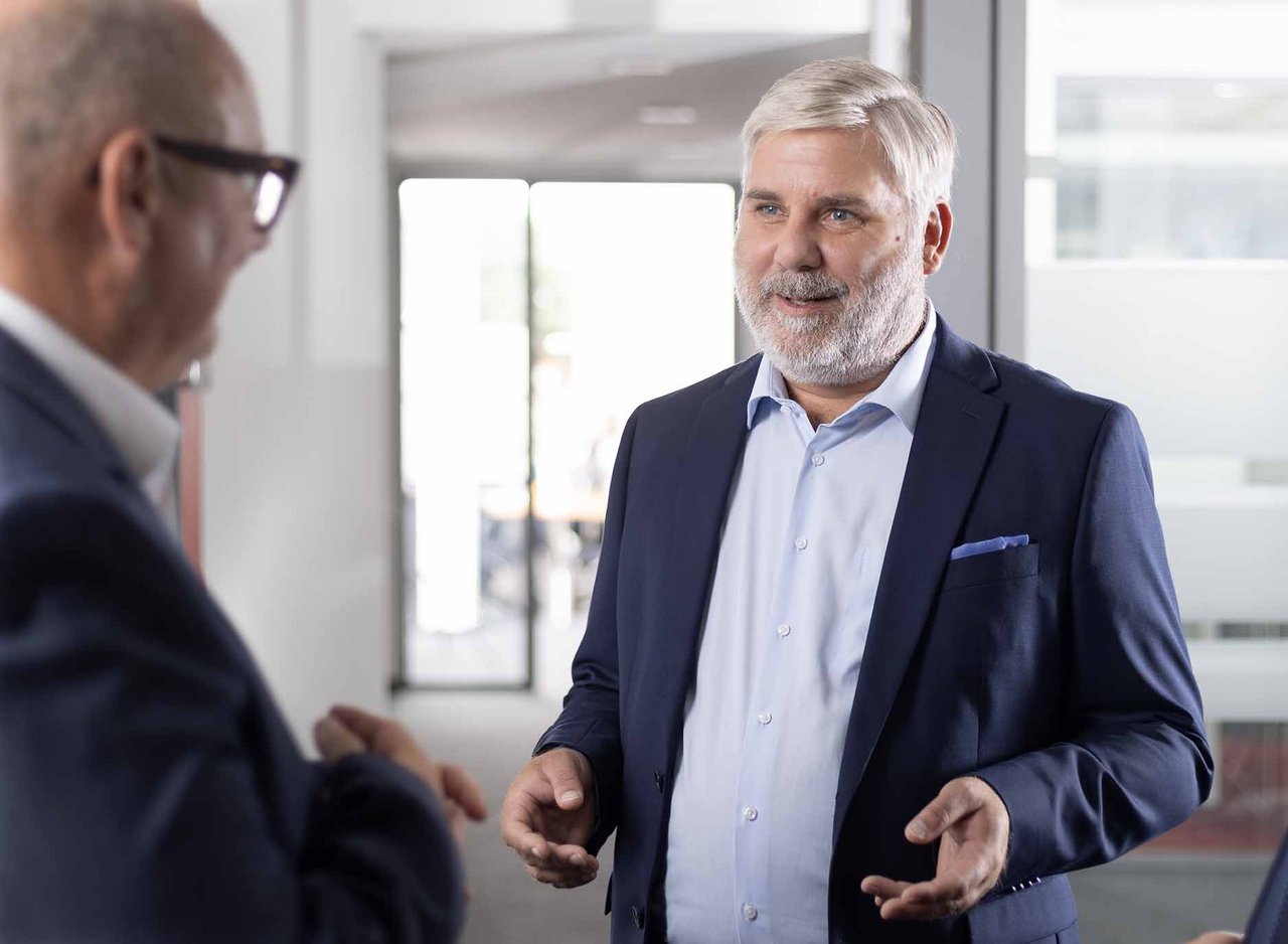 Marc Kampfenkel im offenen Gespraech mit Kanzlei-Partner im Büro